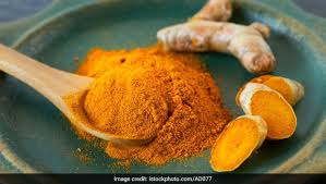 turmeric powder in a wooden spoon kept on a plate